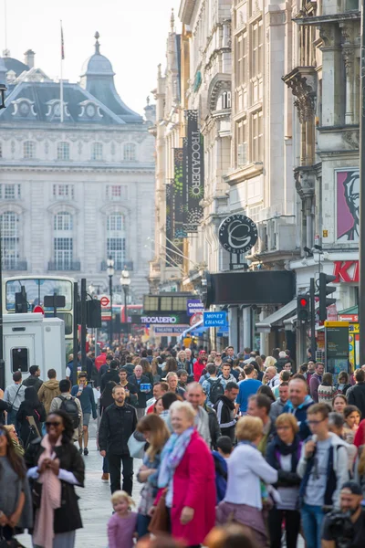 :Lots of people, tourists and Londoners walking via Leicester square, the famous destination of London for night life, cinemas, restaurants and bars — Stock Photo, Image