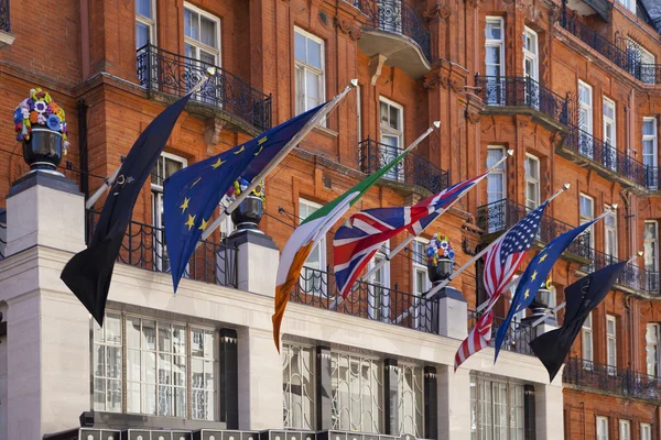 LONDRES, Reino Unido - 3 de junio de 2014: Banderas internacionales sobre la entrada principal del lujoso hotel Claridges — Foto de Stock