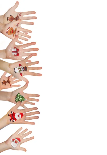 Kinderhände erheben sich mit bemalten Weihnachtssymbolen: Weihnachtsmann, Weihnachtsbaum, Schneemann, Regenhirsch, Geschenkbox — Stockfoto