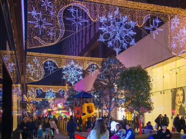 Stratford Köyü kare ve büyük alışveriş merkezi Noel ışıkları ve bir sürü insan çevresinde alışveriş süslenmiş