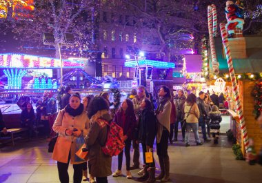 London, Leicester square traditional fun fair with stools, carrousel, prises to win and Christmas activity. People and families enjoying Christmas mood night out clipart