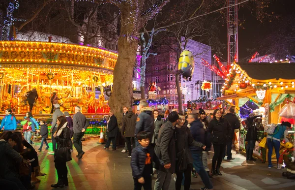 Londres, Leicester plaza tradicional feria de la diversión con taburetes, carrusel, sorpresas para ganar y la actividad de Navidad. Personas y familias disfrutando de la noche de Navidad — Foto de Stock