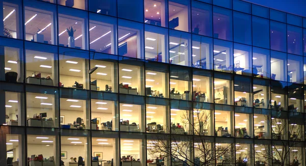 Londres, bloco de escritórios com muitas janelas iluminadas e funcionários de escritório atrasados dentro. Cidade de Londres ária de negócios ao entardecer . — Fotografia de Stock