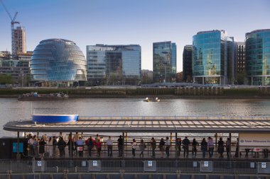 LONDON, UK - APRIL15, 2015: Modern buildings on the south bank of river Thames walk. Office centre, theatre and  London city hall building in sun set clipart