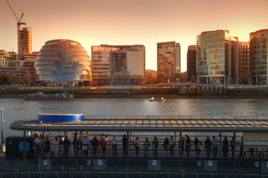 LONDON, UK - APRIL 15, 2015: Modern buildings on the south bank of river Thames walk in sunset. Office centre, theatre and London city hall building clipart