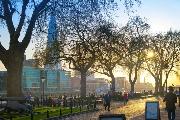 LONDRES, ROYAUME-UNI - 15 AVRIL 2015 : Coucher de soleil sur le parc Tower. Rivière Tamise promenade latérale avec les gens au repos au bord de l'eau — Photo