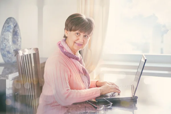 Idosos mulher bonita trabalhando no laptop. Retrato no interior doméstico — Fotografia de Stock
