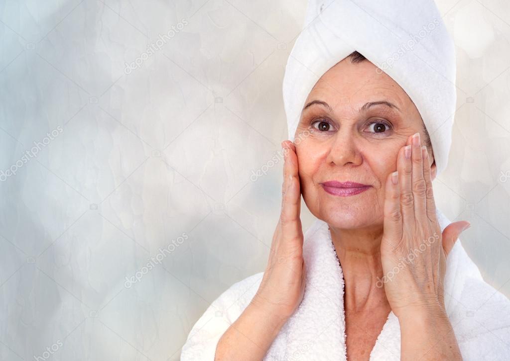 Spa concept. Aged good looking woman with white towel on her head