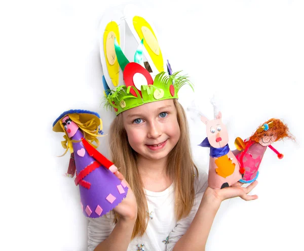 Little girl demonstrating her craft works Easter bonnet, paper dolls and reindeer — Stock Photo, Image