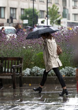 Londra, İngiltere - 17 Eylül 2015: Kadınla şemsiye yağmur altında yürümek. Londra şehri