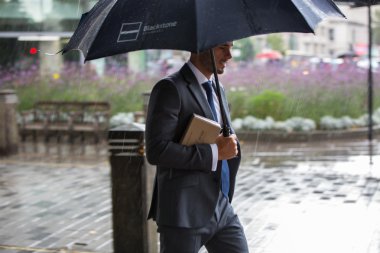 Londra, İngiltere - 17 Eylül 2015: Yağmurda yürümek şemsiye işadamı. Londra şehri