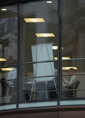 LONDON, UK - SEPTEMBER 19, 2015: Business people having a meeting. View trough the window