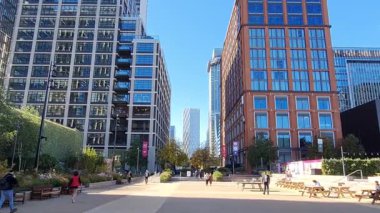 Londra, İngiltere - 7 Ekim 2025: Canary Wharf Meydanı 'nda öğle yemeği vakti yürüyen insanlar. Güneşli bir günde gökdelenlerin ve ofis binalarının güzel manzarası.