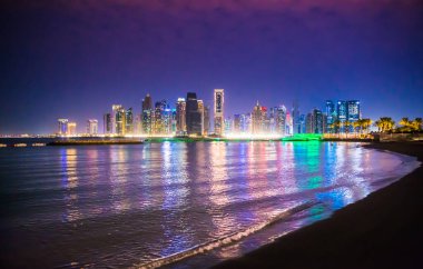 Katar, Doha - 7 Eylül 2025: Gökdelenler gece görüşlü ve suda güzel yansımalı Doha şehir merkezi