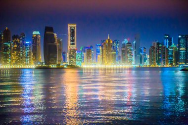 Katar, Doha - 7 Eylül 2025: Gökdelenler gece görüşlü ve suda güzel yansımalı Doha şehir merkezi