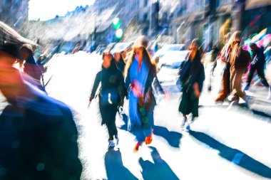 Güneşli bir günde Oxford Sirki 'nde dinamik bir sahne. Farklı yönlerde yürüyen bir kalabalık. Hareket bulanıklığı yoğun kavşağın hareketini ve enerjisini yakalıyor, postmodernizm titreşimi, canlı bir şekilde vurgulanıyor.