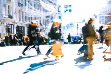 Güneşli bir günde Oxford Sirki 'nde dinamik bir sahne. Farklı yönlerde yürüyen bir kalabalık. Hareket bulanıklığı yoğun kavşağın hareketini ve enerjisini yakalıyor, postmodernizm titreşimi, canlı bir şekilde vurgulanıyor.