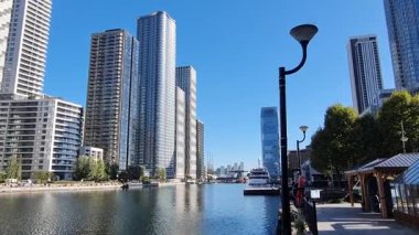 Londra, İngiltere - 7 Ekim 2025: Güneşli bir günde modern gökdelenler ve deniz kenarında yürüyen insanlarla güney limanı manzarası