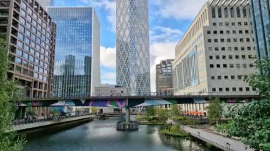 Londra İngiltere - 31 Ekim 2025: Canary Wharf bankacılık ve iş alanında çalışan DLR treni, iç rıhtım manzaralı. Ofis ve şirket binaları