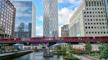 Londra İngiltere - 31 Ekim 2025: Canary Wharf bankacılık ve iş alanında çalışan DLR treni, iç rıhtım manzaralı. Ofis ve şirket binaları