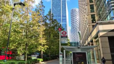 Londra, İngiltere - 23 Ekim 2025 Canary Wharf Meydanı, ofis binaları ve kurumsal gökdelenler. Banka caddesinde yürüyen insanlar, yolda koşan otobüsler ve taksiler.