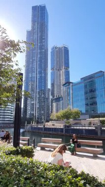 Londra, İngiltere - 7 Ekim 2025: Modern gökdelenler ve deniz kenarında yürüyen insanlar, Canary Wharf