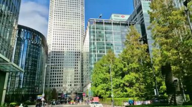 Londra, İngiltere - 23 Ekim 2025 Canary Wharf Meydanı, ofis binası, kurumsal gökdelenler, bankalar. İnsanlar Bank caddesinde yürüyor, otobüsler yolda koşuyor. Modern yoğun iş hayatı