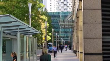 Londra, İngiltere - 23 Ekim 2025 Canary Wharf Meydanı, ofis binası, kurumsal gökdelenler, bankalar. İnsanlar Bank caddesinde yürüyor, otobüsler yolda koşuyor. Modern yoğun iş hayatı