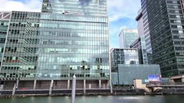 Londra, İngiltere - 7 Ekim 2025: Modern gökdelenler ve deniz kenarında yürüyen insanlar, Canary Wharf