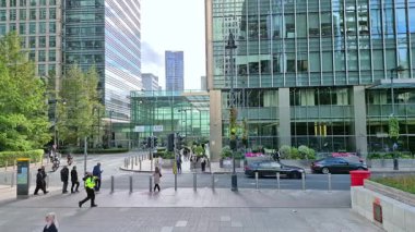 Londra, İngiltere - 23 Ekim 2025 Canary Wharf Meydanı, ofis binası, kurumsal gökdelenler, bankalar. İnsanlar Bank caddesinde yürüyor, otobüsler yolda koşuyor. Modern yoğun iş hayatı