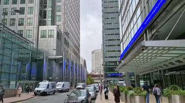 Londra, İngiltere - 23 Ekim 2025 Canary Wharf Meydanı, ofis binası, kurumsal gökdelenler, bankalar. İnsanlar Bank caddesinde yürüyor, otobüsler yolda koşuyor. Modern yoğun iş hayatı