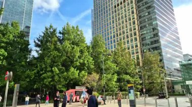 Londra, İngiltere - 23 Ekim 2025 Canary Wharf Meydanı, ofis binası, kurumsal gökdelenler, bankalar. İnsanlar Bank caddesinde yürüyor, otobüsler yolda koşuyor. Modern yoğun iş hayatı