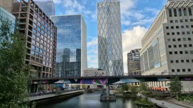 Londra, İngiltere - 23 Ekim 2025: Canary Wharf, Bank caddesi, ofis binaları, cam gökdelenler, suya park ve yürüyen insanlar orta rıhtım manzarası