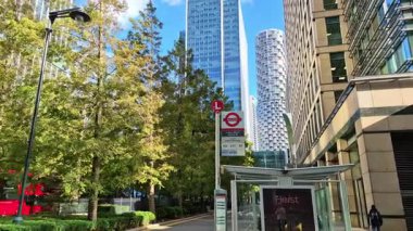 Londra, İngiltere - 23 Ekim 2025 Canary Wharf Meydanı, ofis binası, kurumsal gökdelenler, bankalar. İnsanlar Bank caddesinde yürüyor, otobüsler yolda koşuyor. Modern yoğun iş hayatı