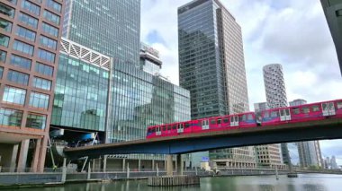 Londra, İngiltere - 23 Ekim 2025: Canary Wharf, Bank caddesi, ofis binaları, cam gökdelenler, suya park ve yürüyen insanlar orta rıhtım manzarası