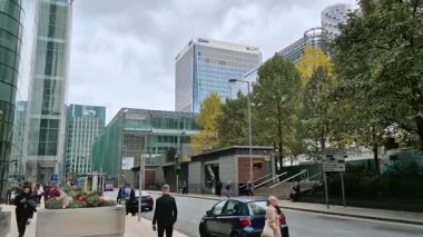 Londra, İngiltere - 23 Ekim 2025 Canary Wharf Meydanı, ofis binası, kurumsal gökdelenler, bankalar. İnsanlar Bank caddesinde yürüyor, otobüsler yolda koşuyor. Modern yoğun iş hayatı