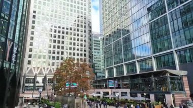 Londra, İngiltere - 23 Ekim 2025 Canary Wharf Meydanı, ofis binası, kurumsal gökdelenler, bankalar. İnsanlar Bank caddesinde yürüyor, otobüsler yolda koşuyor. Modern yoğun iş hayatı