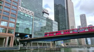 Londra İngiltere - 31 Ekim 2025: Canary Wharf bankacılık ve iş alanında çalışan DLR treni, iç rıhtım manzaralı. Ofis ve şirket binaları