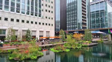 Londra, İngiltere - 23 Ekim 2025: Canary Wharf, Bank caddesi, ofis binaları, cam gökdelenler, suya park ve yürüyen insanlar orta rıhtım manzarası