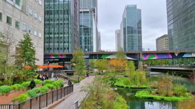 Londra, İngiltere - 23 Ekim 2025: Canary Wharf, Bank caddesi, ofis binaları, cam gökdelenler, suya park ve yürüyen insanlar orta rıhtım manzarası