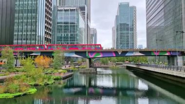 Londra İngiltere - 31 Ekim 2025: Canary Wharf bankacılık ve iş alanında çalışan DLR treni, iç rıhtım manzaralı. Ofis ve şirket binaları