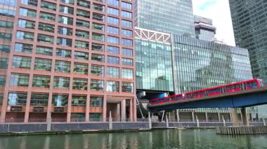 Londra İngiltere - 31 Ekim 2025: Canary Wharf bankacılık ve iş alanında çalışan DLR treni, iç rıhtım manzaralı. Ofis ve şirket binaları