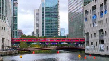 Londra İngiltere - 31 Ekim 2025: Canary Wharf bankacılık ve iş alanında çalışan DLR treni, iç rıhtım manzaralı. Ofis ve şirket binaları
