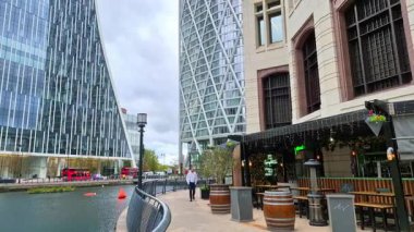 Londra, İngiltere - 23 Ekim 2025: Canary Wharf, Bank caddesi, ofis binaları, cam gökdelenler, suya park ve yürüyen insanlar orta rıhtım manzarası