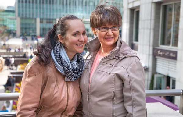 Outdoor family portrait of pension age Mother and her daughter in the city, smiling and looking around. Two generation, happiness and care concept — Stock Photo, Image