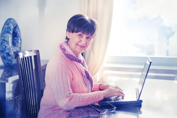Idosos mulher bonita trabalhando no laptop. Retrato no interior doméstico — Fotografia de Stock