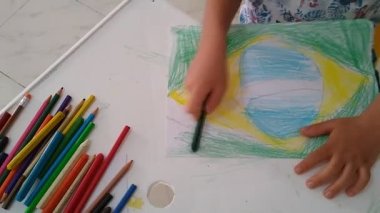 Salvador, Bahia / Brezilya - Kasım 18, 2020: Çocuk okul faaliyetleri sırasında Brezilya bayrağını çizerken görülüyor.