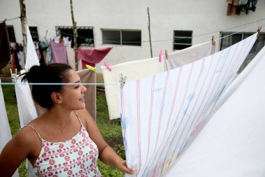 Mata de Sao Joao, Bahia, Brezilya - 1 Ekim 2020: Mata de Sao Joao şehrinin popüler bir semtinde çamaşır ipinde giysilerini tutan kadın. * * * Yerel altyazı * *