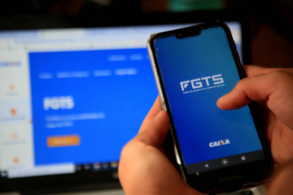 salvador, bahia, brazil - december 8, 2020: person with cell phone trying to access the FGTS page on the Caixa Economica Federal website in the city of Salvador.