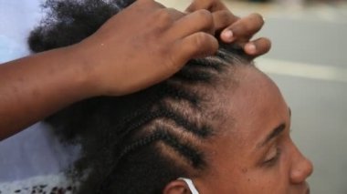 Salvador, Bahia, Brezilya - 14 Aralık 2020: Genç bir adam Salvador şehir merkezindeki bir caddede siyah bir kadının saçında güve yaparken görüldü.. 